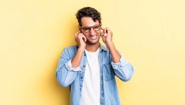 İspanyol yakışıklı adam sinirli, stresli ve sinirli görünüyor, iki kulağını da kapatıyor.