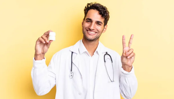 ヒスパニック系のハンサムな男は笑顔と幸せそうに見える勝利や平和をジェスチャー 医師用ボトル薬のコンセプト — ストック写真