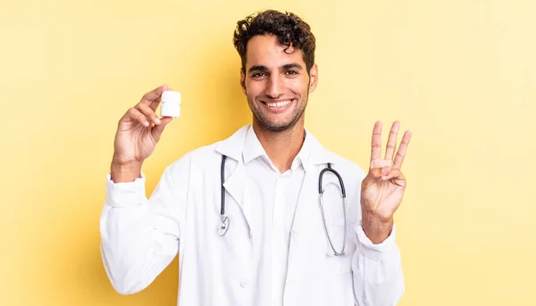 ヒスパニック系のハンサムな男笑顔と友好的に見える 3番目を示しています 医師用ボトル薬のコンセプト — ストック写真