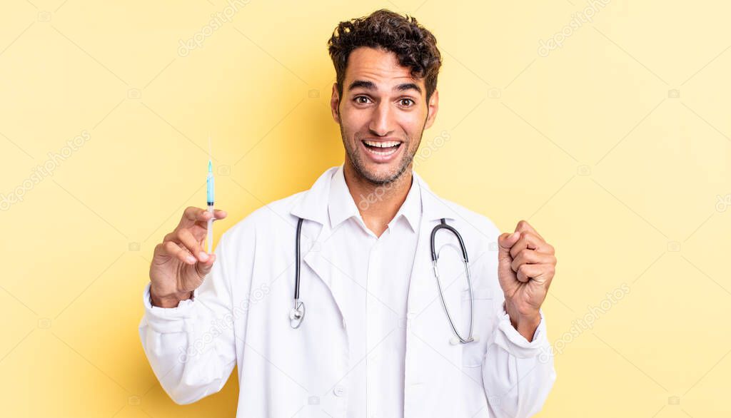 hispanic handsome man feeling shocked,laughing and celebrating success physician and srynge concept