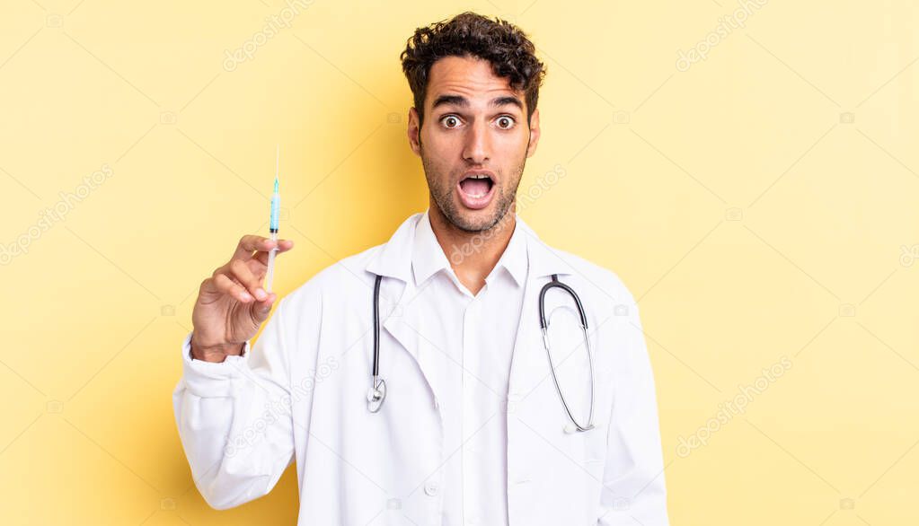 hispanic handsome man looking very shocked or surprised physician and srynge concept