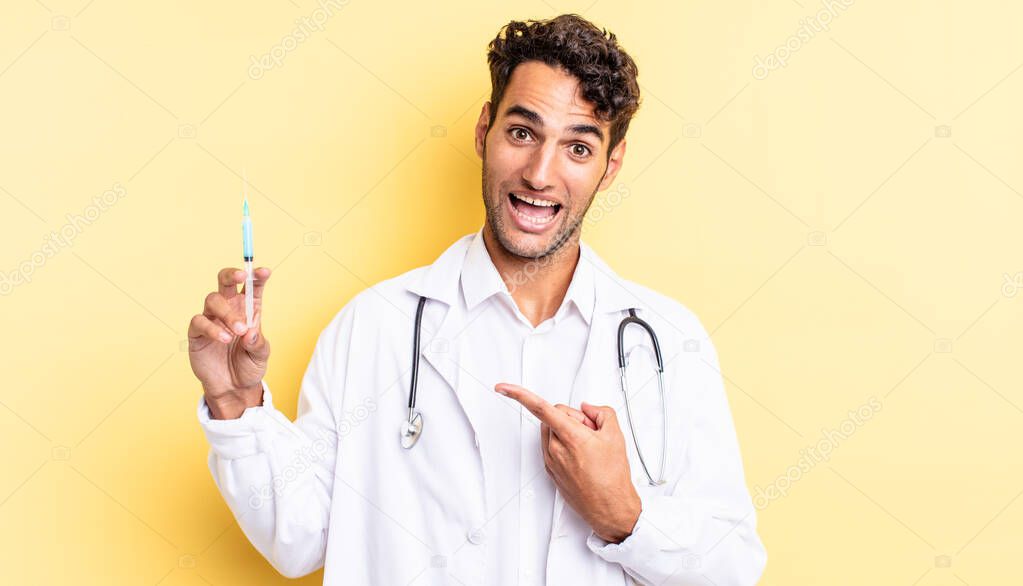 hispanic handsome man looking excited and surprised pointing to the side physician and srynge concept