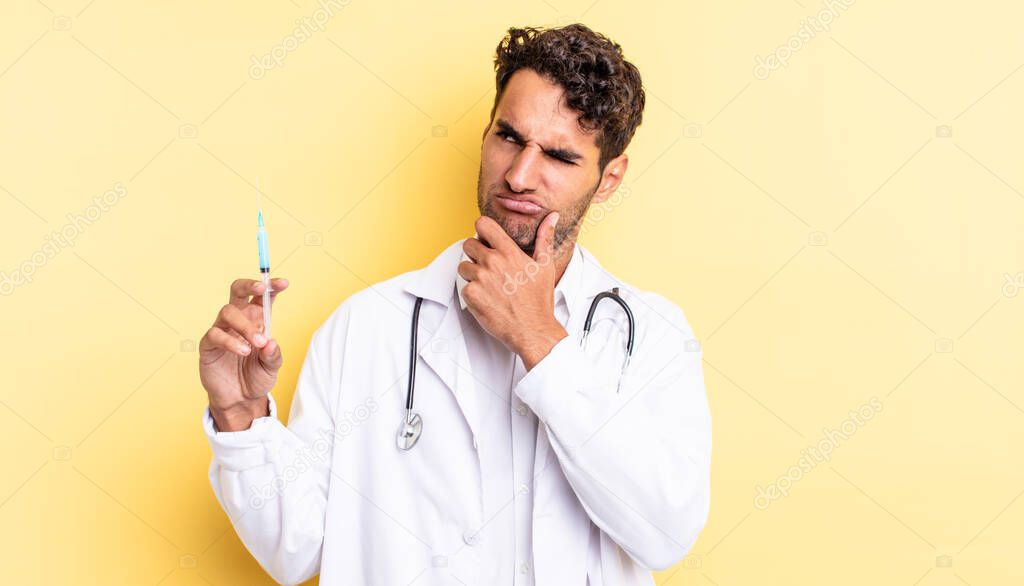 hispanic handsome man thinking, feeling doubtful and confused physician and srynge concept
