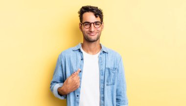 İspanyol yakışıklı adam gururlu, kendinden emin ve mutlu görünüyor, gülümsüyor ve kendini işaret ediyor.