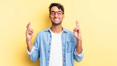 İspanyol yakışıklı adam gülümsüyor ve endişeyle iki parmağını çapraz yapıyor.
