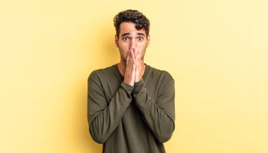 İspanyol yakışıklı adam endişeli, üzgün ve korkmuş hissediyor, elleriyle ağzını kapatıyor.