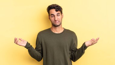 hispanic handsome man shrugging with a dumb and puzzled expression