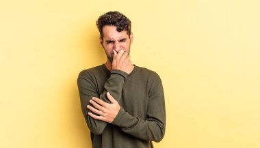 İspanyol yakışıklı adam iğreniyor, burnunu tutuyor.