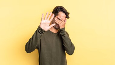 İspanyol yakışıklı adam elleriyle yüzünü kapatıyor.