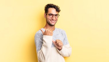 İspanyol yakışıklı adam neşeyle gülümsüyor ve tesadüfen fotokopi alanını gösteriyor.