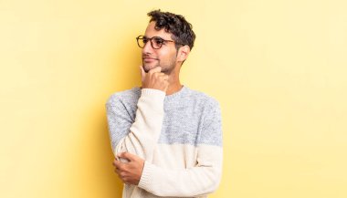 Hispanik yakışıklı adam düşünceli, meraklı ya da hayal kuruyor.