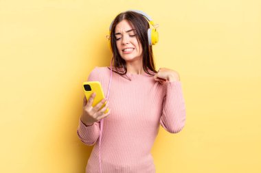 Genç İspanyol kadın stresli, endişeli, yorgun ve hayal kırıklığına uğramış hissediyor. kulaklıklar ve telefon konsepti