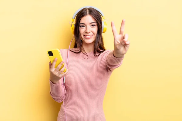 Joven Mujer Hispana Sonriendo Luciendo Amigable Mostrando Número Dos Auriculares —  Fotos de Stock