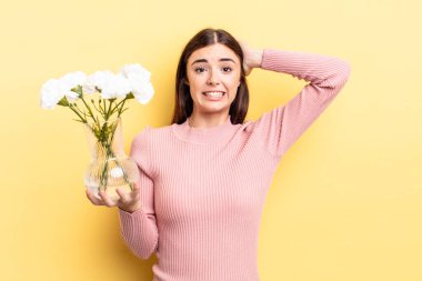 Genç İspanyol kadın stresli, endişeli ya da korkmuş hissediyor, elleri başının üstünde. saksı konsepti