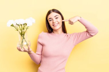 Genç İspanyol kadın kendine güvenerek gülümsüyor ve kendi gülüşünü gösteriyor. saksı konsepti