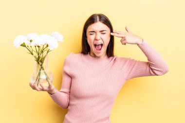 Genç İspanyol kadın mutsuz ve stresli görünüyor, intihar jesti silah işareti yapıyor. saksı konsepti