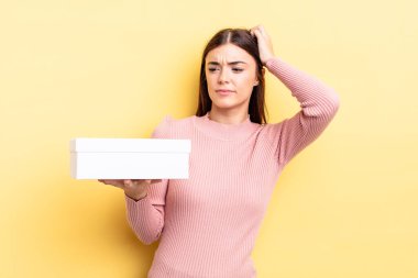 Genç İspanyol kadın şaşkın ve kafası karışık, kaşınan bir kafa hissediyor. boş kutu kavramı