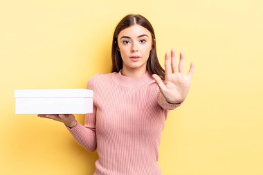 Genç İspanyol kadın ciddi görünüyor. Avuç içini gösteriyor. Durdurma hareketi yapıyor. boş kutu kavramı