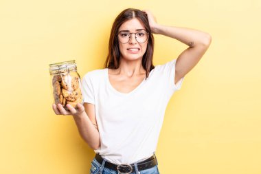 Genç İspanyol kadın stresli, endişeli ya da korkmuş hissediyor, elleri başının üstünde. kurabiye şişesi konsepti