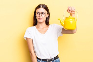 Genç İspanyol kadın üzgün, üzgün ya da kızgın hissediyor ve yana bakıyor. çaydanlık konsepti