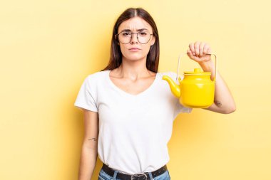 Genç İspanyol kadın üzgün ve mızmızlanıyor. Mutsuz bir bakışı var ve ağlıyor. çaydanlık konsepti