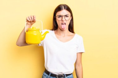 Genç İspanyol kadın iğreniyor, sinirleniyor ve dili dışarı çıkıyor. çaydanlık konsepti