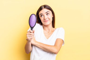 Genç İspanyol kadın omuz silkiyor, kafası karışık ve kararsız. saç fırçası konsepti