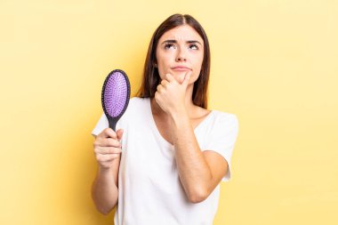 Genç İspanyol kadın düşünüyor, kuşkulu ve şaşkın hissediyor. saç fırçası konsepti