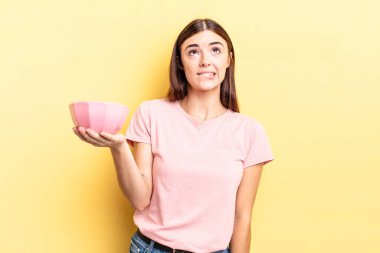 Genç İspanyol kadın şaşkın ve şaşkın görünüyor. boş kase kavramı