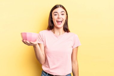 Genç İspanyol kadın mutlu ve hoş bir şekilde şaşırmış görünüyor. boş kase kavramı