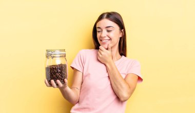 Genç İspanyol kadın mutlu ve kendinden emin bir ifadeyle gülümsüyor. Elleri çenesinde. kahve çekirdeği konsepti