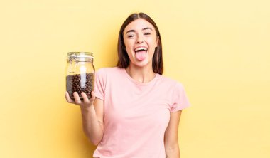 Neşeli ve asi tavırları olan, şaka yapan ve dilini dışarı çıkaran genç İspanyol bir kadın. kahve çekirdeği konsepti