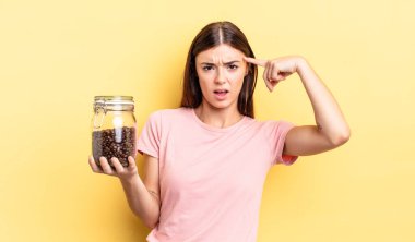 Genç İspanyol kadın şaşkın ve şaşkın hissediyor, senin deli olduğunu gösteriyor. kahve çekirdeği konsepti