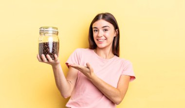 Genç İspanyol kadın neşeyle gülümsüyor, mutlu hissediyor ve bir konsept gösteriyor. kahve çekirdeği konsepti