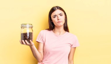 Genç İspanyol kadın üzgün ve mızmızlanıyor. Mutsuz bir bakışı var ve ağlıyor. kahve çekirdeği konsepti