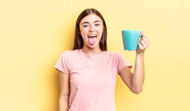 Neşeli ve asi tavırları olan, şaka yapan ve dilini dışarı çıkaran genç İspanyol bir kadın. Kahve fincanı konsepti