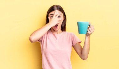 Genç İspanyol bir kadın şok olmuş, korkmuş ya da korkmuş görünüyor. Yüzü elle kapatılmış. Kahve fincanı konsepti