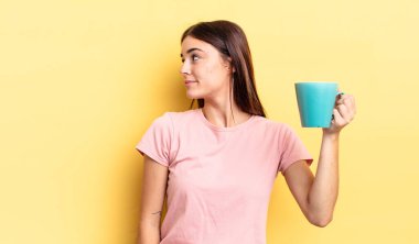 Profil görünümlü genç İspanyol kadın hayal mi kuruyor yoksa hayal mi kuruyor? Kahve fincanı konsepti