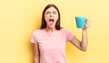 Genç İspanyol kadın agresif bir şekilde bağırıyor, çok kızgın görünüyor. Kahve fincanı konsepti