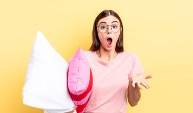 Genç İspanyol kadın şok olmuş ve şaşırmış hissediyor. Pijama ve yastık konsepti