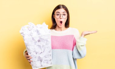 Genç İspanyol kadın şaşırmış ve şok olmuş görünüyor. Çenesi düşmüş ve elinde bir nesne tutuyor. başarısızlık çöp konsepti