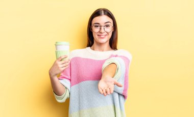 Genç İspanyol kadın mutlu bir şekilde gülümsüyor ve bir konsept sunuyor. kahve konseptini kaldır.