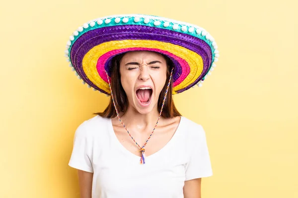 stock image young hispanic woman shouting aggressively, looking very angry. mexican hat concept