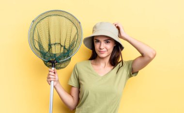 Genç İspanyol kadın şaşkın ve kafası karışmış, balık ağı kavramını tırmalıyor.