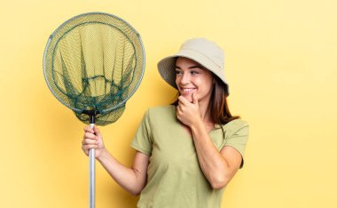 Genç İspanyol kadın mutlu, kendinden emin bir ifadeyle gülümsüyor ve elleri çenesinde balık ağı konseptiyle.