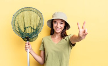 Genç İspanyol kadın gülümseyen ve mutlu görünen, işaret eden zafer ya da barış balığı ağı konsepti