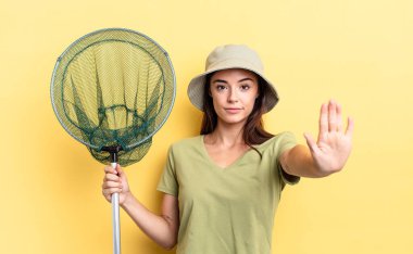 Genç İspanyol kadın ciddi görünüyor. Avuç içini gösteriyor. Jest balık ağı kavramını durduruyor.