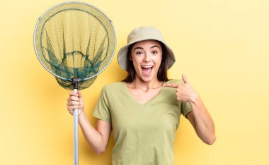 Genç İspanyol kadın mutlu hissediyor ve heyecanlı bir balık ağı konseptiyle kendini işaret ediyor.