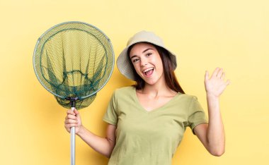 Genç İspanyol kadın mutlu bir şekilde gülümsüyor, el sallıyor, sizi selamlıyor ve balık ağı kavramını selamlıyor.