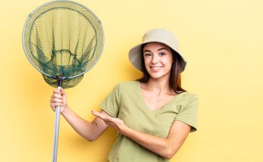 Genç İspanyol kadın neşeyle gülümsüyor, mutlu hissediyor ve balık ağı konseptini gösteriyor.